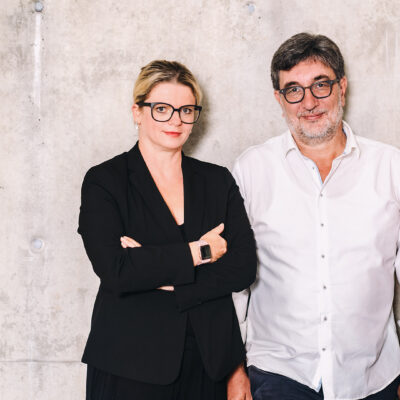 Susanne Schaper und Stefan Hartmann stehen vor einer Waschbetonwand